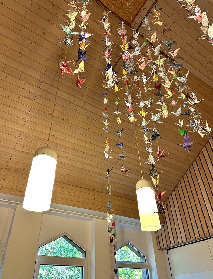 Man sieht eine Girlande aus Papier-Kranichen von der Decke herabhängen
