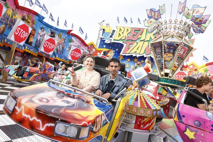 Zwei Personen fahren mit einem Kirmesfahrgeschäft