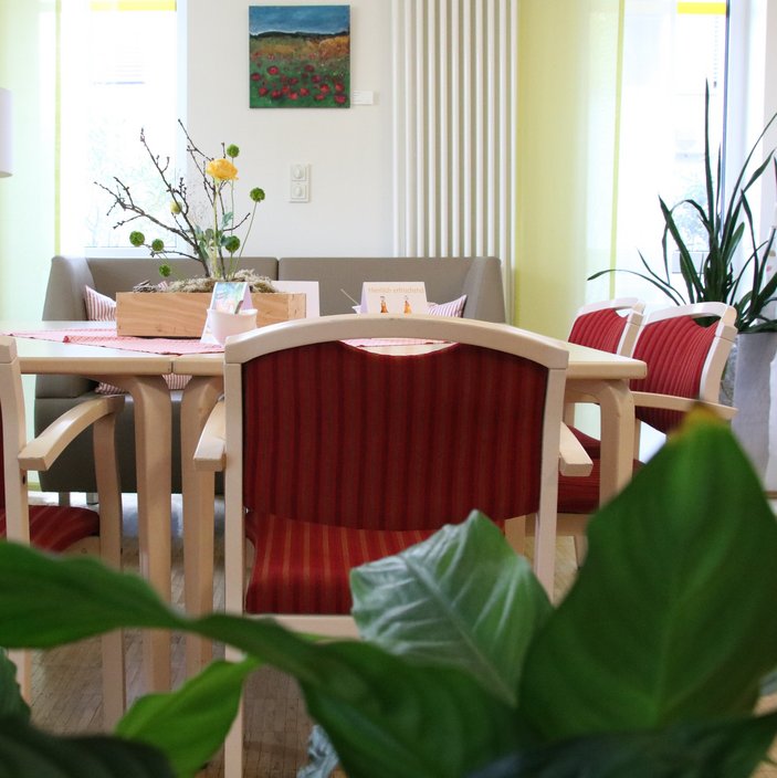 Ein Tisch mit roten Stühlen; an der Wand hängt ein kleines Gemälde.