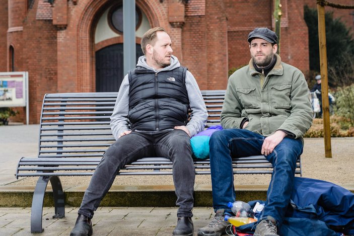Zwei Männer sitzen auf einer Bank und unterhalten sich