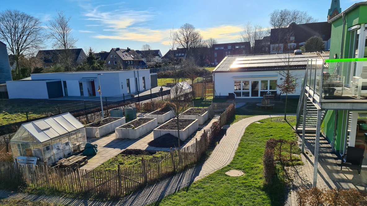 Ansicht auf die Anlage mit Gewächshaus und Hochbeeten