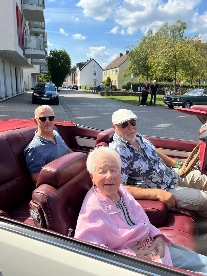Drei Seniorinnen und ein Junior-Fahrer im offenen Oldtimer-Cabrio
