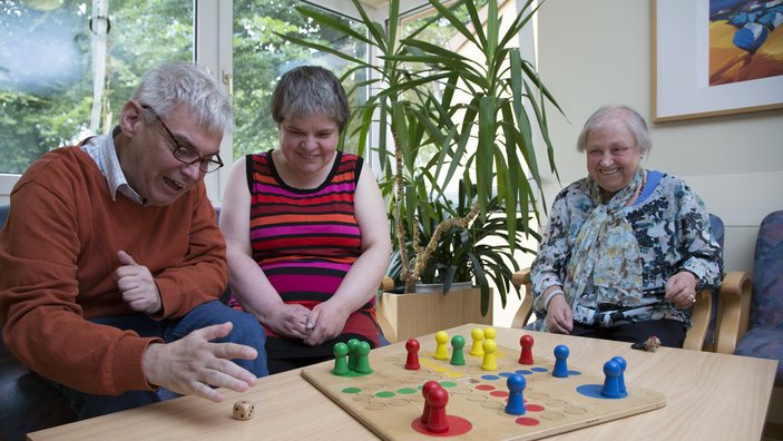 Drei Personen spielen Mensch-ärgere-dich-nicht