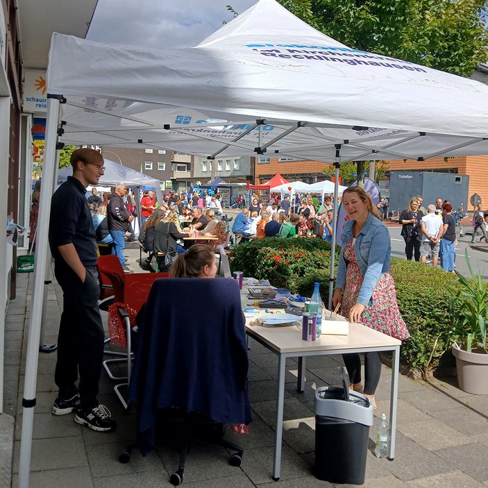 Verschiedene Personen reden unter dem Diakone-Pavillion-Dach miteinander