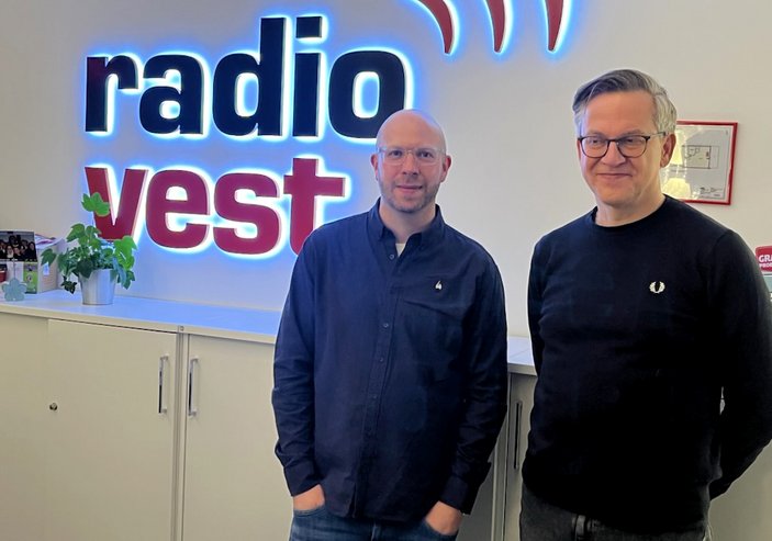 die beiden Integrationshelfer vor dem leuchtenden Radio Vest - Logo