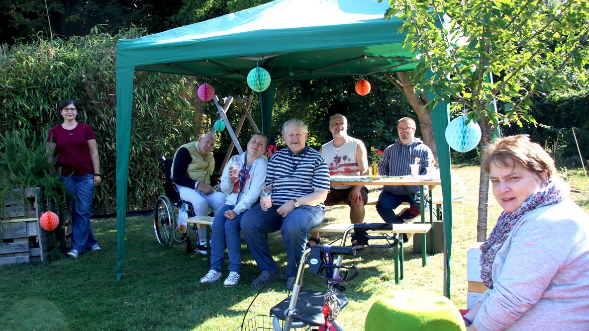 Menschen sitzen unter einem Pavillon im Garten