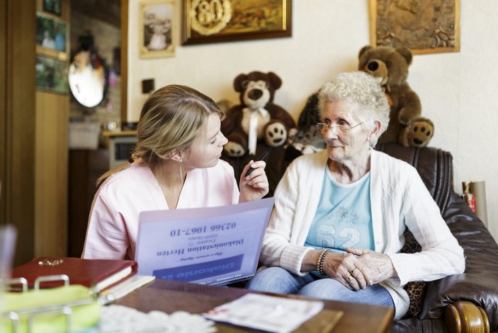 Pflegekraft unterhält sich mit Patientin
