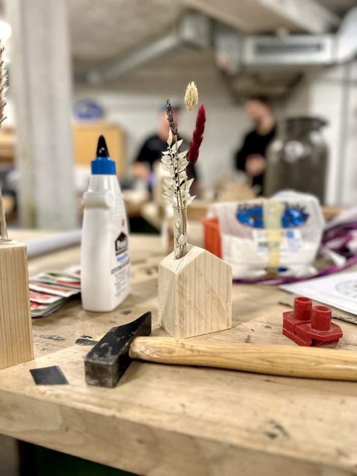 Man sieht eine kreativ hergestellte Vase aus Holz in der Trockenblumen stecken