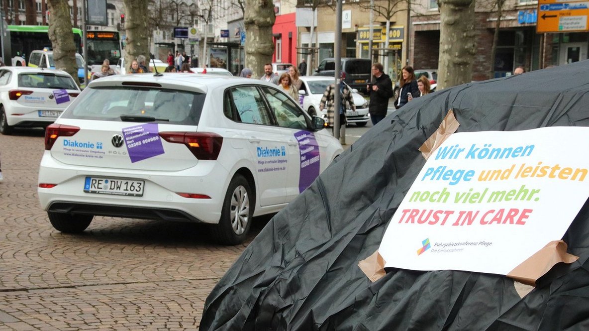 Diakoniestation auf Rathausplatz, danaben ein Zettel auf dem Steht "Wir können Pflege und leisten noch viel mehr."