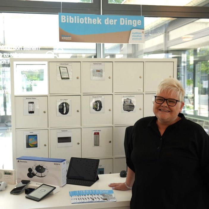 Frau steht vor Bibliothek der Dinge und lächelt in die Kamera