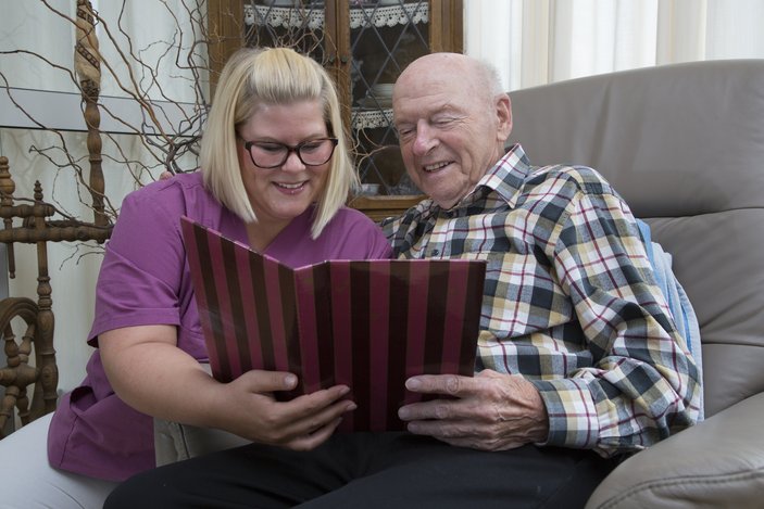 Pflegekraft liest mit Senior in einem Buch