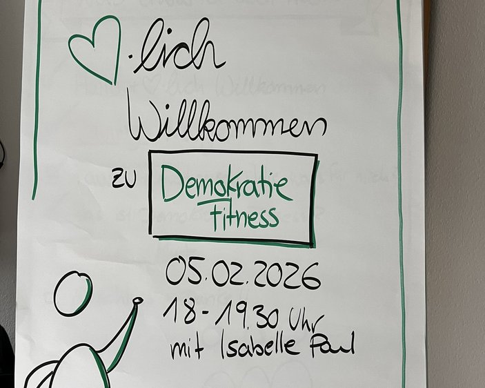 Foto eines Flip-Charts mit dem Schriftzug "Herzlich Willkomen zur Demokratie-Fitness"